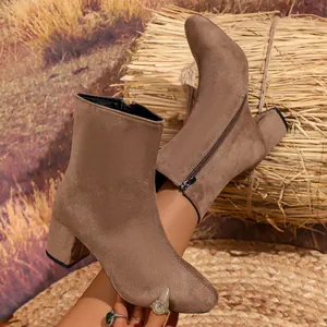 Side detail view of brown suede ankle boots featuring metallic zipper and block heel