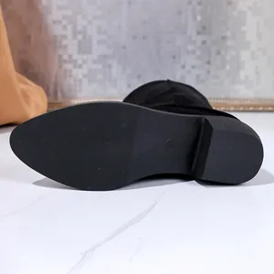 Close-up detail of the anti-slip rubber sole and chunky heel on black suede boots