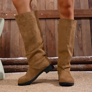 Slouchy brown suede-like tall knight boots shown in a rustic outdoor setting