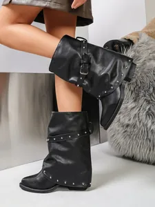 Detailansicht schwarzer Slouch-Stiefel mit silbernen Nieten-Schnallenriemen und spitzer Kappe.