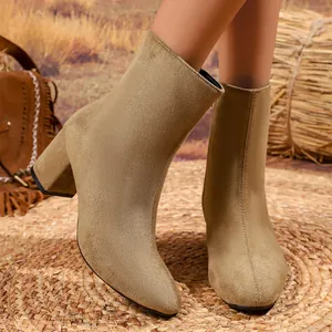 Close-up of khaki suede ankle boots with pointed toe and square heel on rustic mat