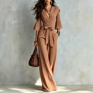 Full length detail of a French deep V brown jumpsuit with waist belt and wide leg pants.