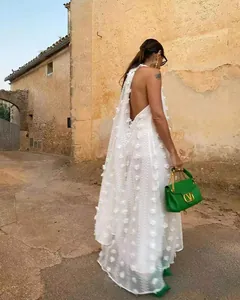 Détail de la robe blanche dos nu avec des appliques de fleurs 3D pour les vacances d'été.