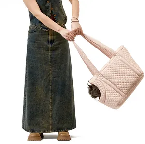 Female model holding a quilted pink pet carrier bag with a small cat peeking out
