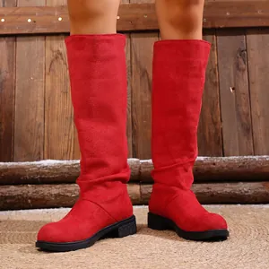 Detailed close-up of vibrant red slouchy western cowboy boots with rustic wood background