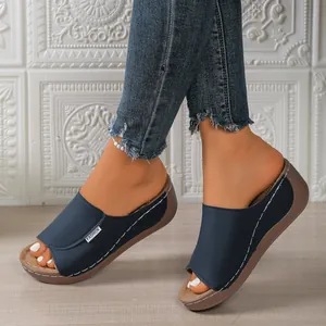 Close-up of blue peep-toe wedge sandals with thick platform soles and white stitching.