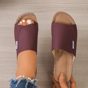 Detailed view of women's burgundy peep-toe platform wedge slippers on wood background