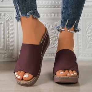 Close-up of burgundy peep-toe wedge platform sandals worn with denim jeans and anklet.