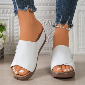 Detailed view of white wedge platform slippers with fish-toe design and brown soles.