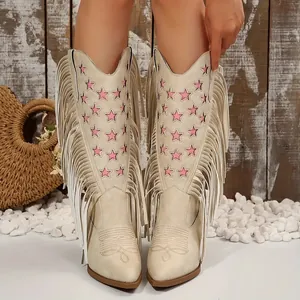 Detail van crèmekleurige cowboylaarzen met roze sterborduursel en lange zijfranjes.