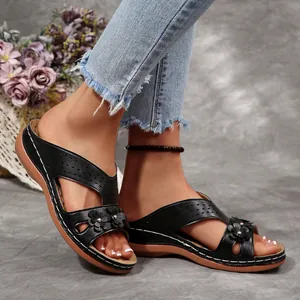 Detaillierte Nahaufnahme schwarzer Retro-Keilsandalen mit Blumen auf einem Modell
