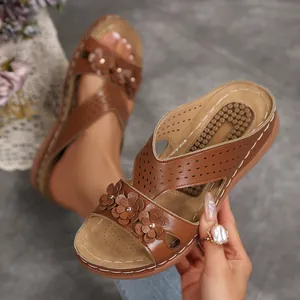 Detailaufnahme brauner Vintage-Keilsandalen mit dekorativen Blumen und Lochmuster.