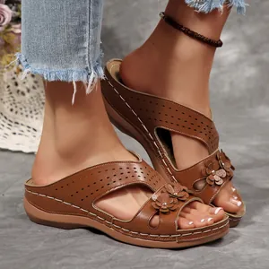 Detailansicht der braunen Keilsandaletten im Retro-Stil mit 3D-Blumen und Laser-Cutouts