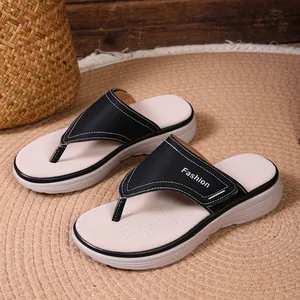 Détail de sandales compensées noires avec logo Fashion sur fond tissé naturel.