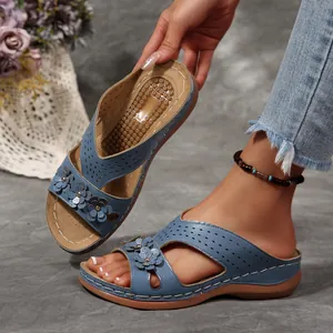Detailansicht blauer Vintage-Keilsandalen mit Blumenakzenten und Lochmuster-Details
