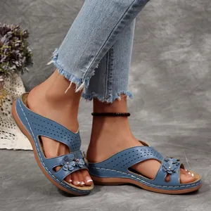 Nahaufnahme blauer Vintage Keilsandaletten mit Blumenakzenten an einem Modell getragen
