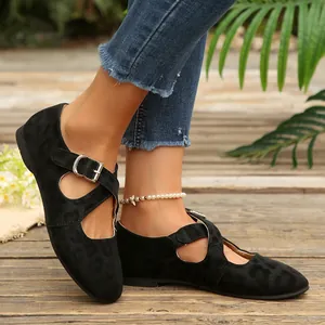 Primo piano di scarpe Mary Jane nere leopardate con cinturini incrociati ai piedi.