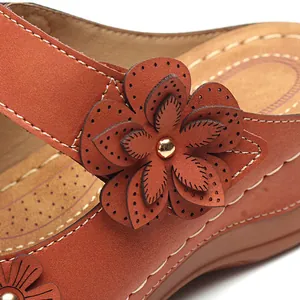 Detail von braunen Vintage-Keilsandalen mit lasergeschnittenen Blumen und Nähten