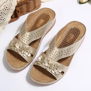 Detail der goldenen Vintage Keilsandaletten mit Lasercut-Riemen und 3D-Blumen.