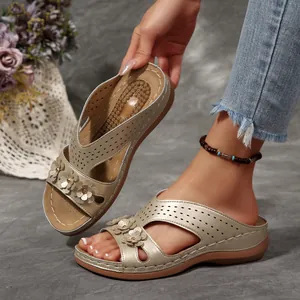 Nahaufnahme goldener Keilsandaletten mit Retro-Blumendekor und Lasercut-Muster