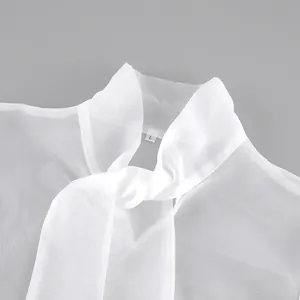 Primer plano de blusa de malla blanca transparente con un delicado lazo en el cuello