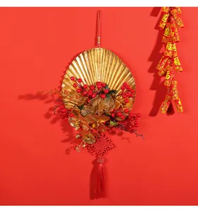 Close-up of festive New Year hanging ornament with golden fan and vibrant red berries.