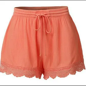 Gros plan d'un short décontracté corail pour femme avec dentelle délicate et cordon.