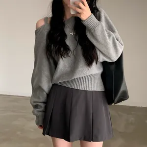 Dettaglio di un maglione grigio a maniche lunghe con spalle scoperte e vestibilità ampia.