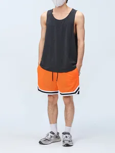 Full body view of men's orange mesh athletic shorts with lining on model