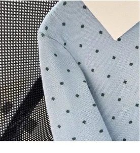 Detailed macro view of light blue knitted cardigan fabric with dark blue polka dot pattern