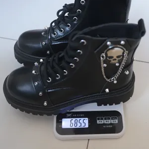 Bottines punk noires à clous pesées à 685,5 grammes sur une balance électronique