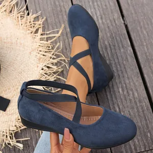 Primer plano de zapatos de cuña en ante azul marino con tiras cruzadas sobre tarima de madera