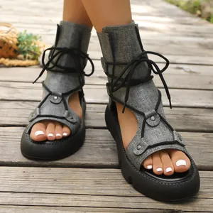 Stilvolle graue Gladiator-Sandalen aus Leinen mit schwarzen Schnürsenkeln auf Holz