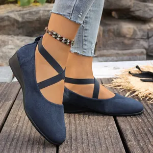 Primer plano de zapatos de gamuza azul para mujer con correas elásticas cruzadas.