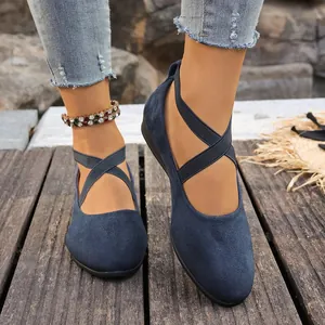 Primer plano de zapatos de ante azul marino con correas elásticas cruzadas.