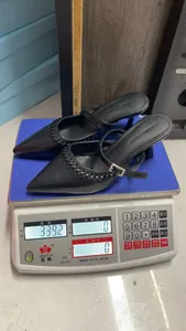 Detail of black pointed-toe Mary Jane heels showing 339.2g weight on digital scale