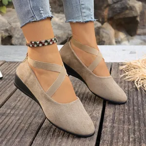 Elegantes zapatos de cuña de ante kaki con tiras cruzadas en los pies de modelo