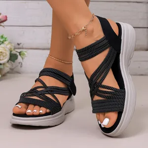 Detailweergave van zwarte sportieve sandalen met elastische bandjes en witte sleehak