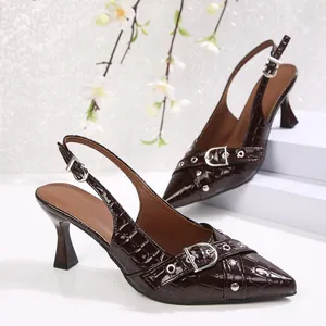 Detail view of dark brown crocodile-embossed slingback heels featuring silver buckle accents