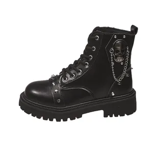 Détail de bottines Martin punk en cuir noir avec tête de mort et chaînes en métal