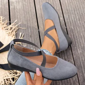 Vista detallada de zapatos de cuña en ante gris con correas elásticas cruzadas y suaves.