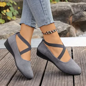 Elegantes zapatos de cuña gris mate con tiras cruzadas usados por modelo en exterior.