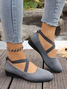 Vista detallada de zapatos de cuña en gamuza gris con correas cruzadas elásticas