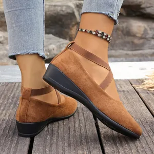 Primer plano de elegantes zapatos de cuña de ante marrón con correas elásticas cruzadas