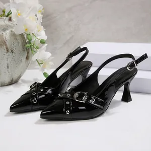Detail of black patent leather slingback heels with pointed toe and buckle rivet accents.