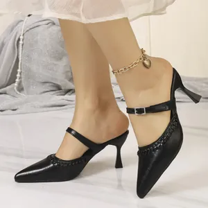 Detailed close-up of elegant black pointed-toe mules featuring braided trim and a buckle strap.