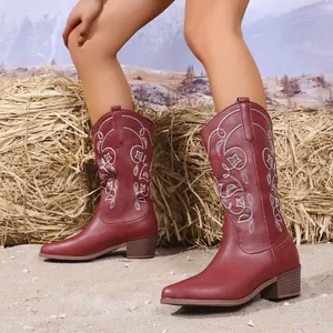 Detail van kastanjebruine western cowboylaarzen met wit bloemenborduursel en blokhak
