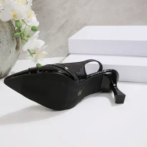 Close-up of black patent leather pointed-toe slingback high heels with buckle detail