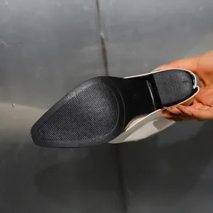Close-up view of the textured black sole and chunky heel of a white fashion boot.