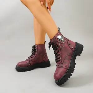 Détail de bottes de combat rétro en cuir bordeaux usé avec motif crâne et chaîne en métal